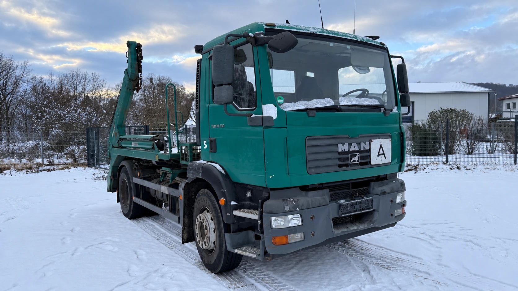 Grüner MAN TGM Absetzkipper im Schnee